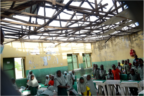 A group of pupils seated on bare floors in a dilapidated classroom at Zhibi LEA Primary School, Dei-Dei, Abuja.